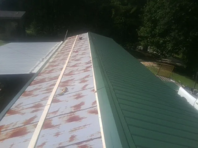 Old rusted panels beside newly installed green metal roofing — Wind Damage Roof Repair by Roofing Brothers in Sparks