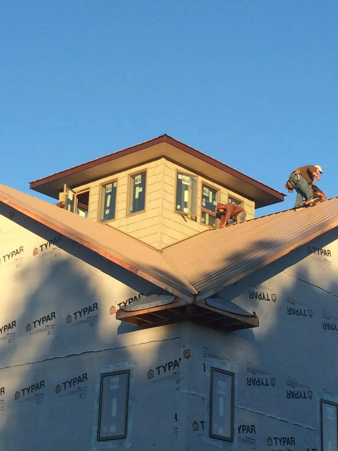 Roofers working around a rooftop cupola on a new metal roof at sunset — Roof Waterproofing in Sparks by Roofing Brothers